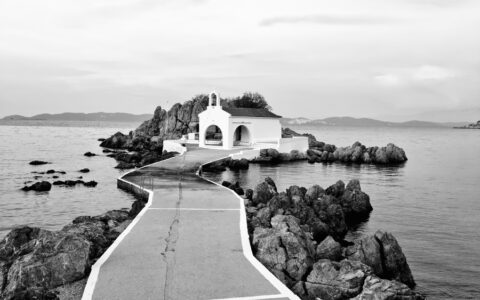 Grayscale Photo of White Concrete Building Near Body of Water